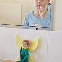 Child brushing teeth in front of a mirror with a Tooth Pixie watching on