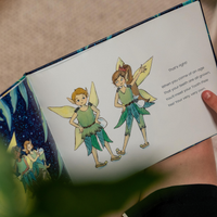 Illustration of two Tooth Pixies on a page from a book held by a person.