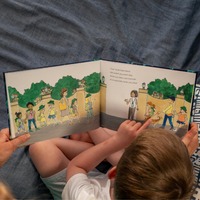 Person reading Tooth Pixies story book with illustrated pages to a child.